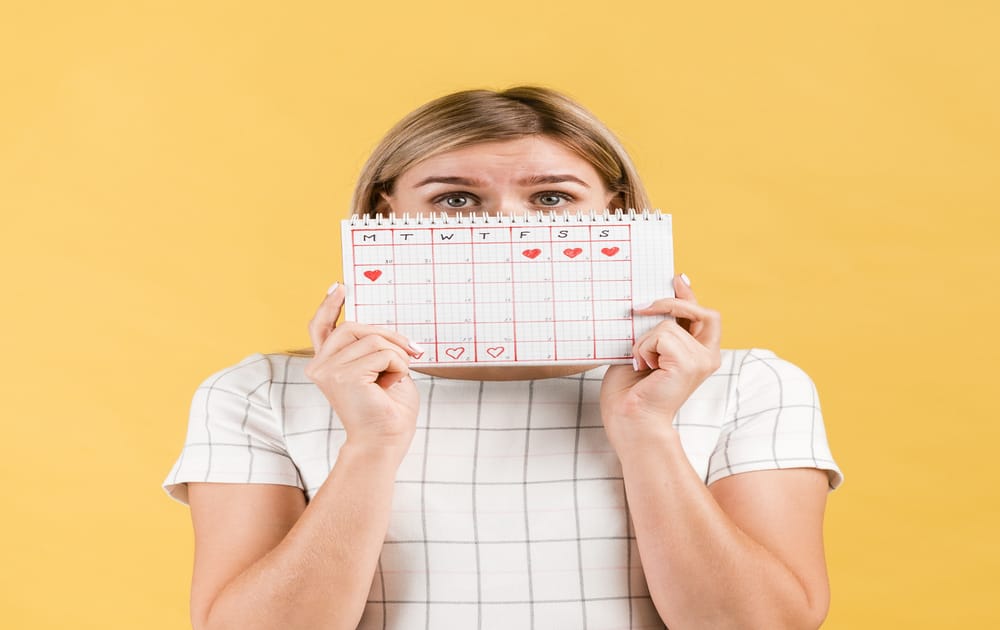 woman covers her face with period calendar 1